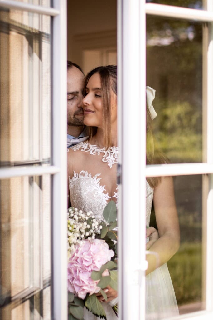Hochzeit Valerie & Pascal, freie Trauung, romantisches Paarfoto durch Fenster aufgenommen.