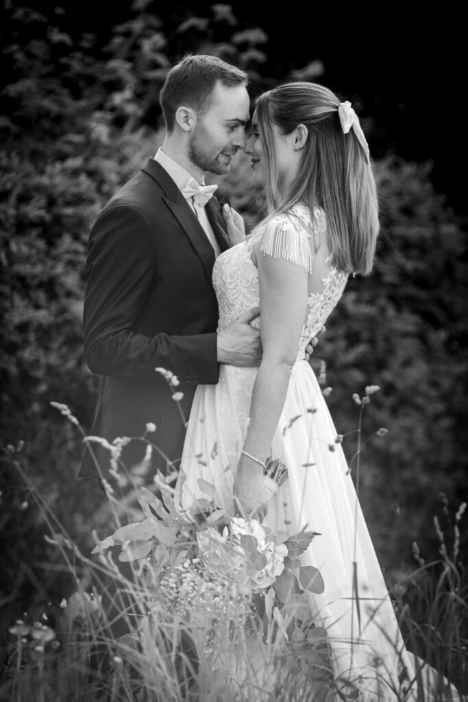 Hochzeitspaar in romantischer Umarmung im Freien, frisch verheiratet, kreative Hochzeitsfotos.
