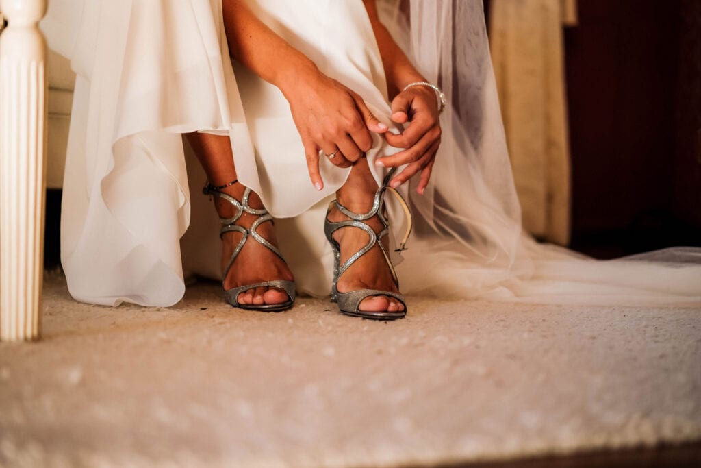 Detailaufnahme von Brautsandalen und Brautkleid.