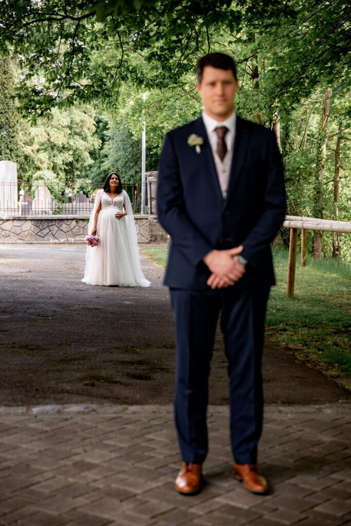 Braut und Bräutigam bei einem First Look ihrer Hochzeit im Park, romantische Atmosphäre.