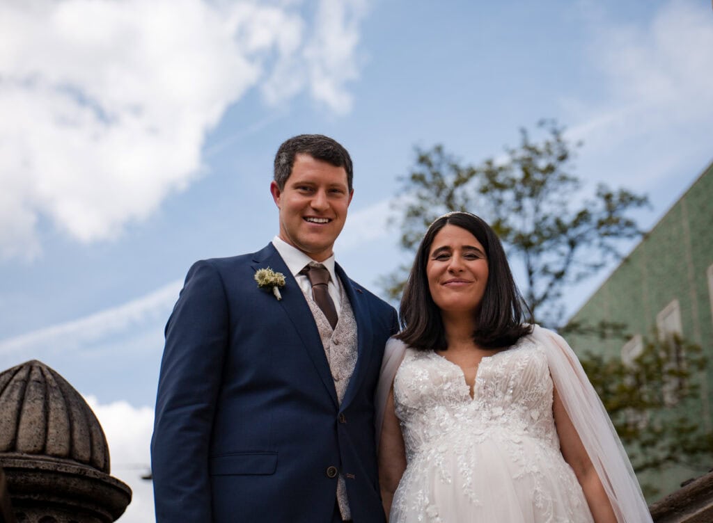 Hochzeitspaar im Freien, lachend und glücklich, bei sonnigem Himmel, festliche Stimmung, Hochzeitsfo.