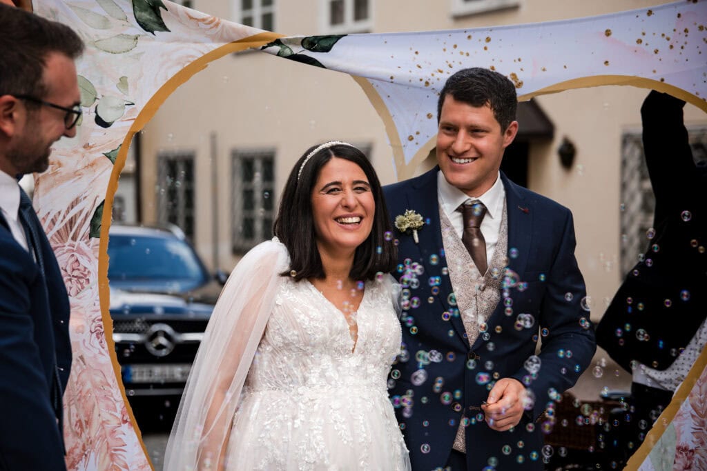 Hochzeitspaar lachend und glücklich, bei einer festlichen Zeremonie im Freien.