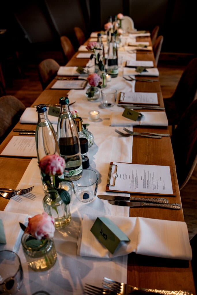 Festlich gedeckter Hochzeitsmahl-Tisch mit Blumen, Kerzen und Getränken.