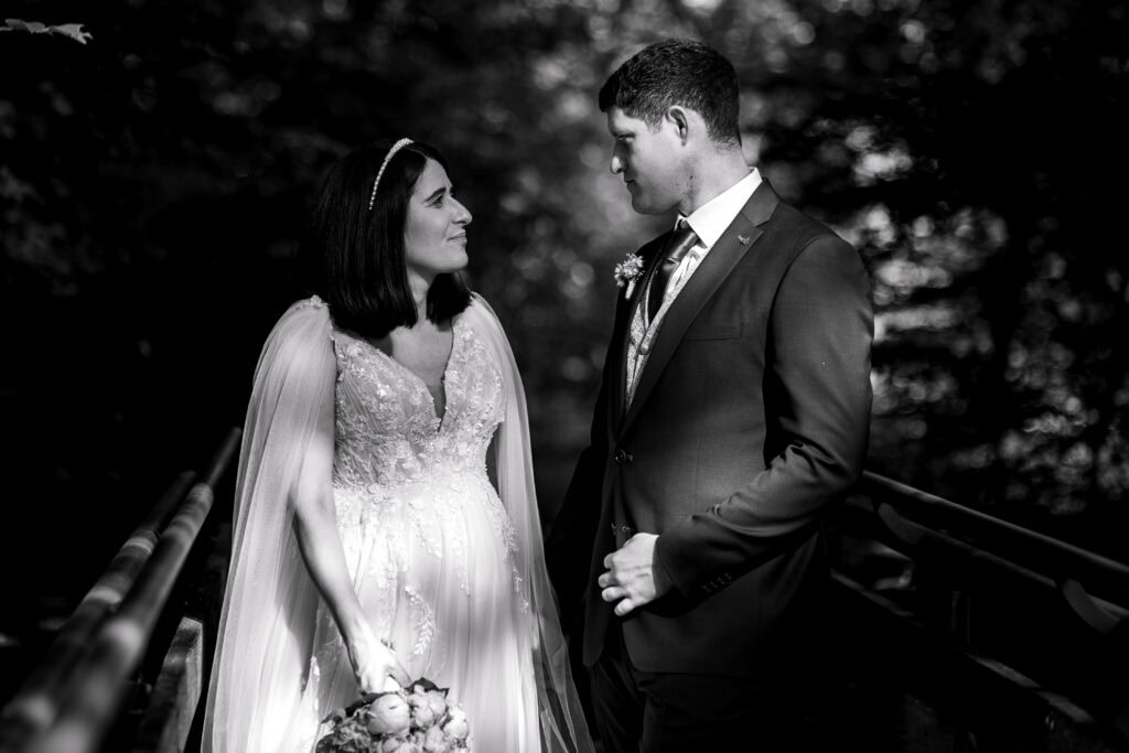 Romantisches Hochzeitsfoto eines Paares im Park, schwarz-weiß, emotionaler Moment.