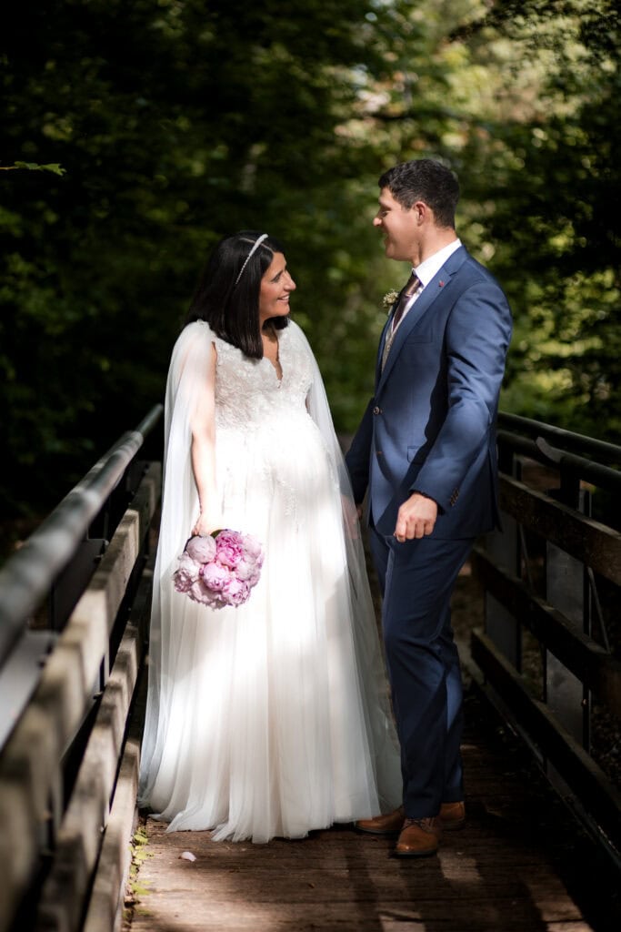 Hochzeitspaar auf Brücke im Park, verliebt und glücklich.