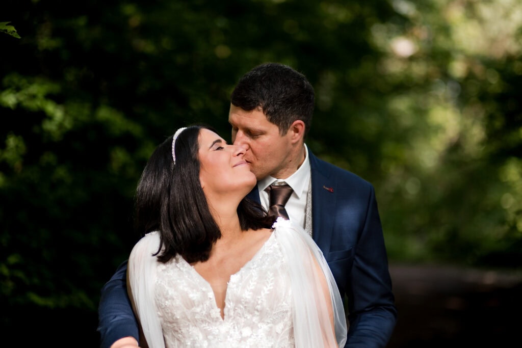 Hochzeitspaar küsst sich im Park, romantische Hochzeitsfotografie von Diane K. Senft.