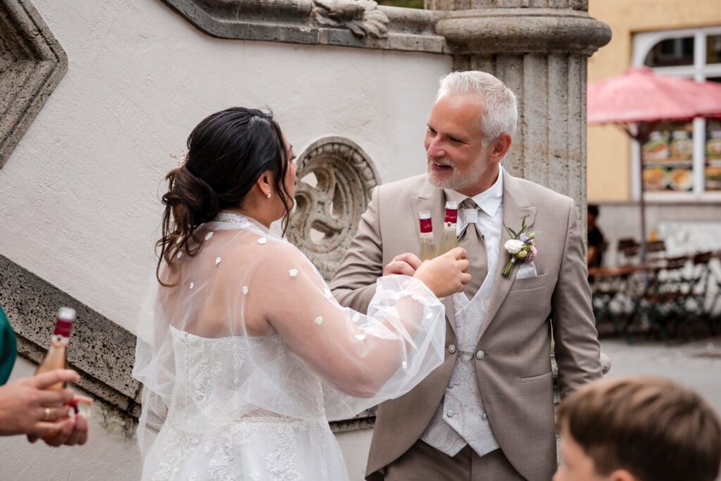Braut und Vater stoßen bei Hochzeit in Fürstenfeldbruck an.