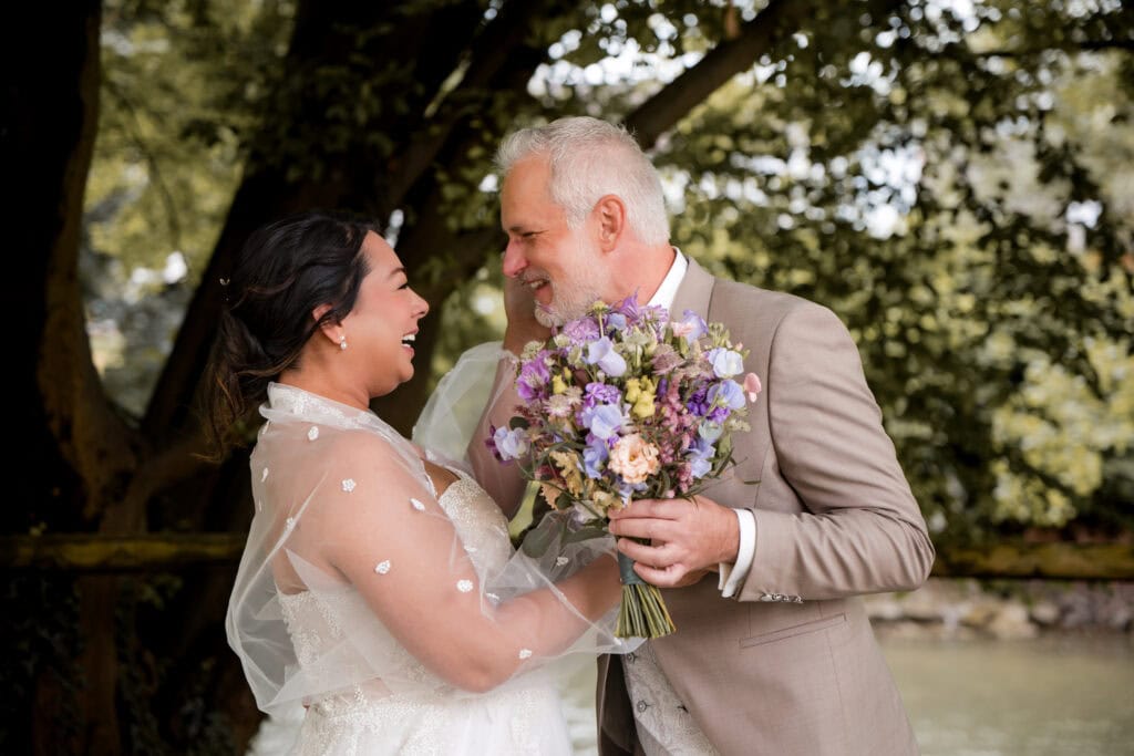 Braut und Bräutigam mit Blumenstrauß bei Hochzeit im Freien.