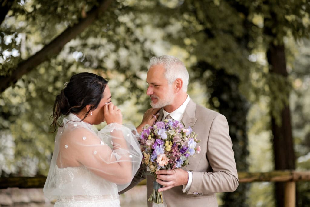 Braut und Vater bei der Hochzeit im Park, emotionaler Moment.