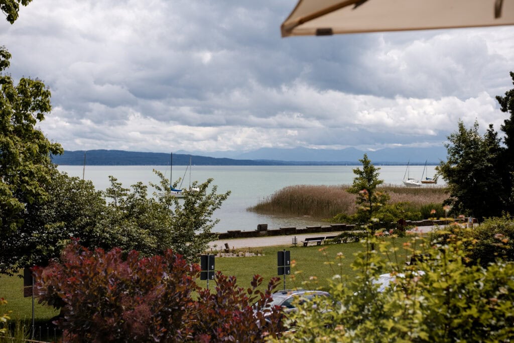 Blick auf den Ammersee mit Booten und bewölktem Himmel.