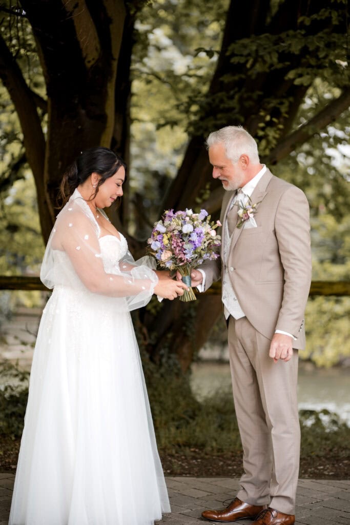 Braut und Bräutigam bei ihrer Hochzeit im Park, Austausch von Blumen.