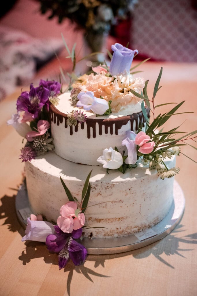 Zwei-stöckige Hochzeitstorte mit Blumen und Schokoladendekor.