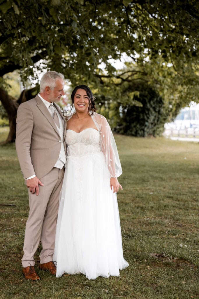 Braut und Vater bei der Hochzeit im Park, lachend und glücklich.