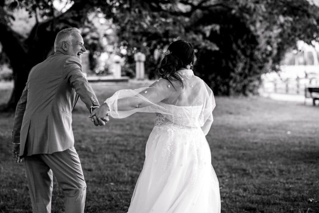 Braut und Vater tanzen im Park bei Sonnenuntergang.
