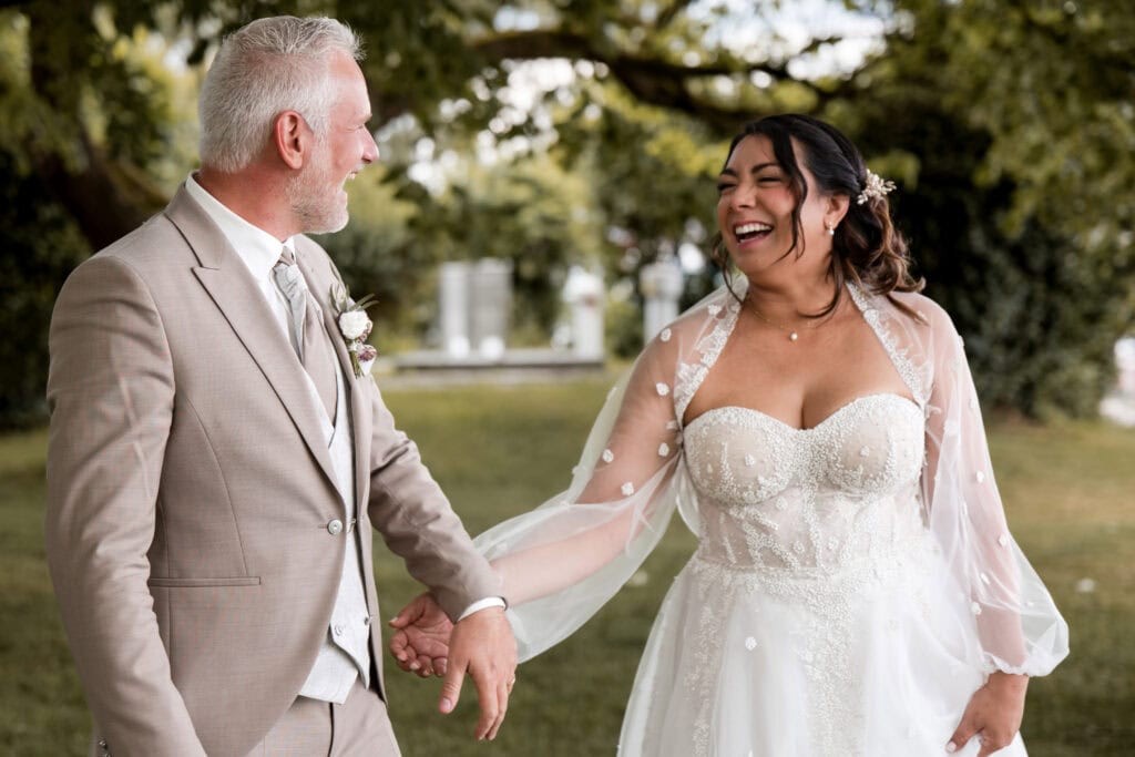 Braut und Vater halten Händchen bei Hochzeit im Park.