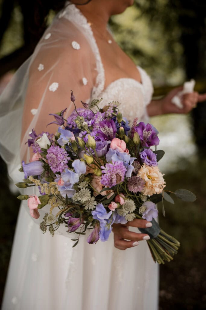 Hochzeitsstrauß mit lila und weißen Blumen bei einer Hochzeit.