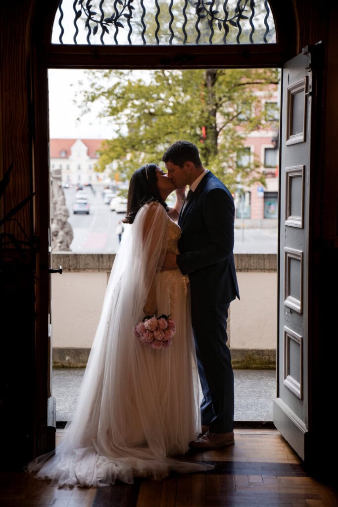 Hochzeitspaar küsst sich im Türrahmen des Standesamtes in Fürstenfeldbruck, Diane K. Senft Hochzeitsfotografie